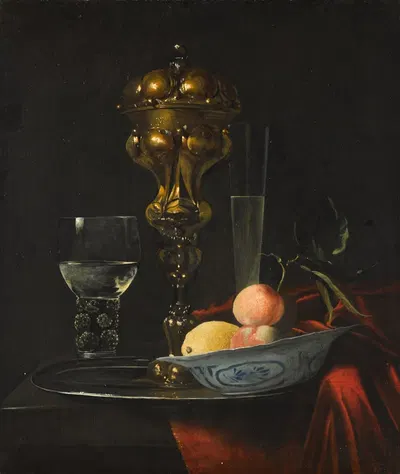 Still life with a gilt cup on a silver plate, a porcelain bowl with fruit, a roemer, and a wine glass, all on a wooden…