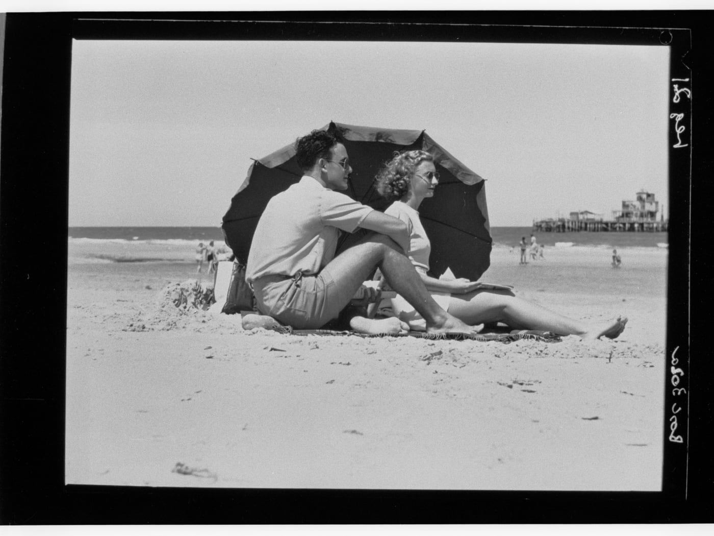 Man and Woman Under Beach Umbrella by State Government Photographer — digital art print download